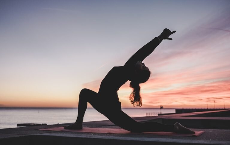 Woman practicing morning yoga in soft sunrise light
