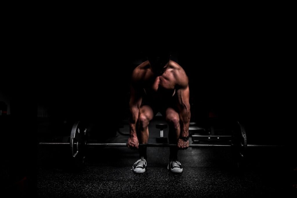 Weightlifter doing a mobility stretch by a barbell