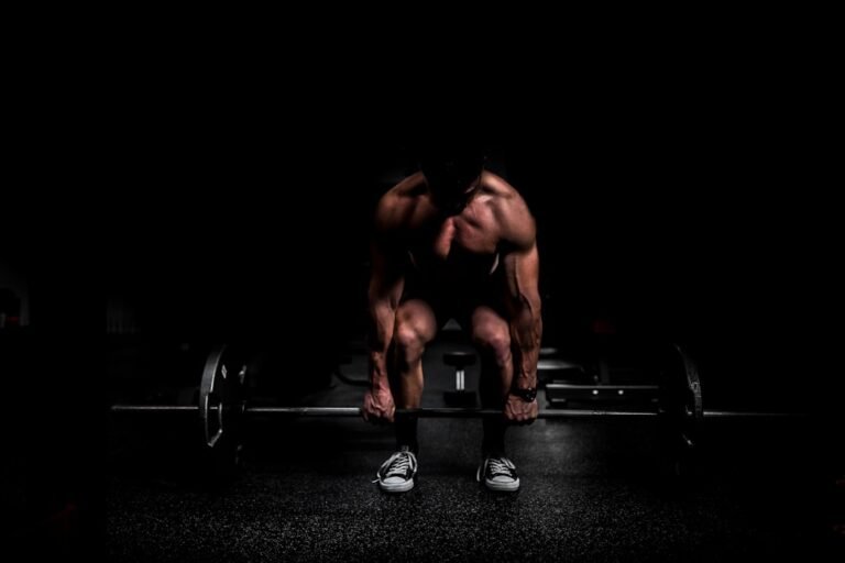 Weightlifter doing a mobility stretch by a barbell